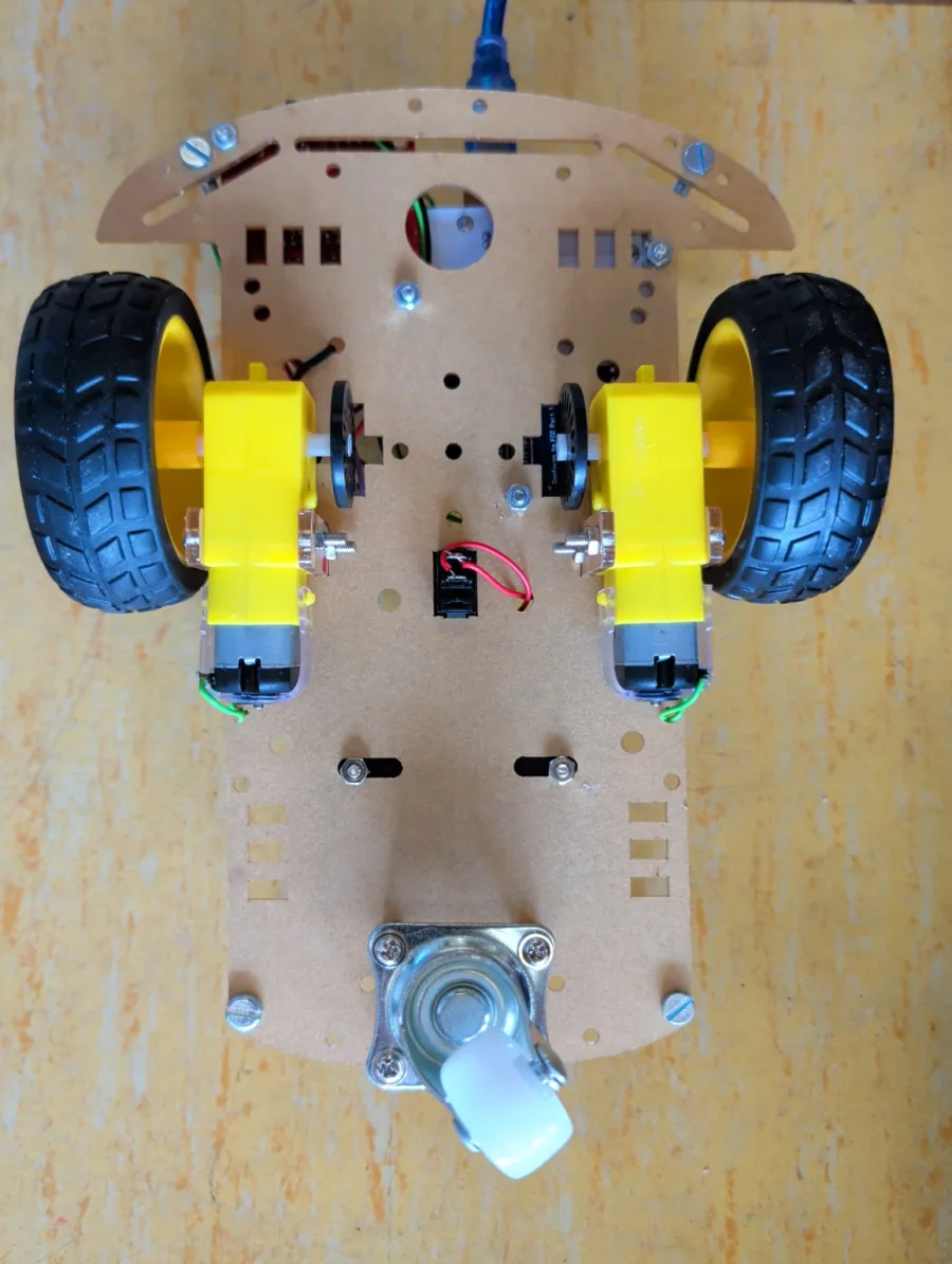 Unterseite des Prototypfahrgestells mit zwei gelben Getriebemotoren, Rädern und Stützrolle